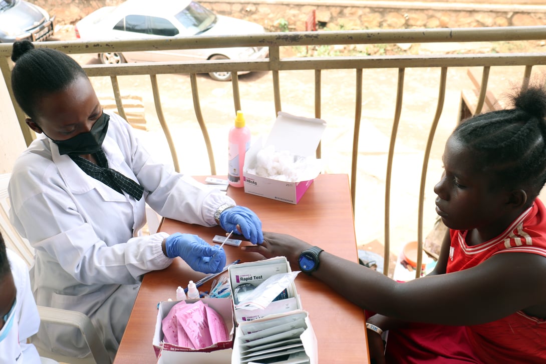 Health worker conducting a hepatitis B blood test on a client in Uganda