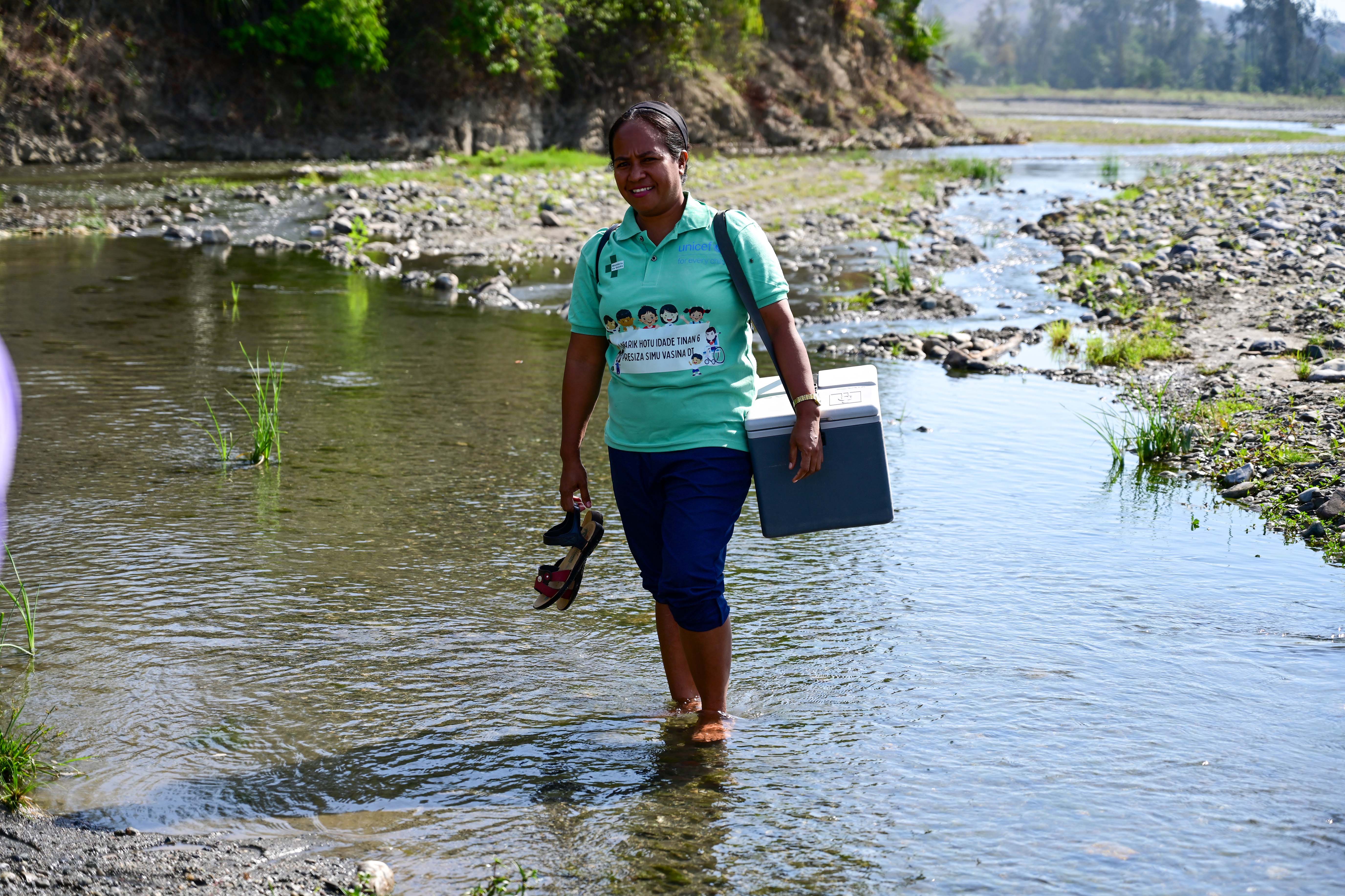 Vaccinator Zulmira Cabral on her way to Remanaru School carrying the vaccine box